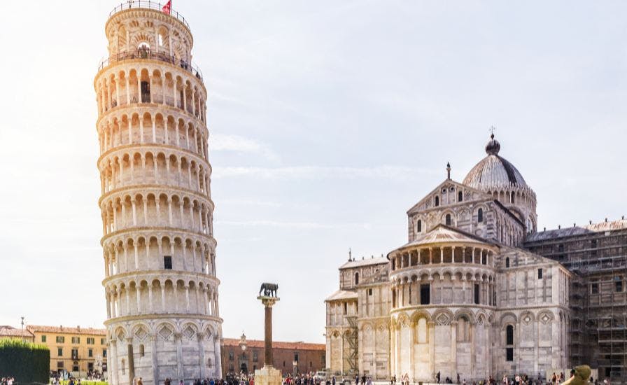 Iconic Leaning Tower of Pisa in Italy, a UNESCO World Heritage Site, tilting against blue sky.