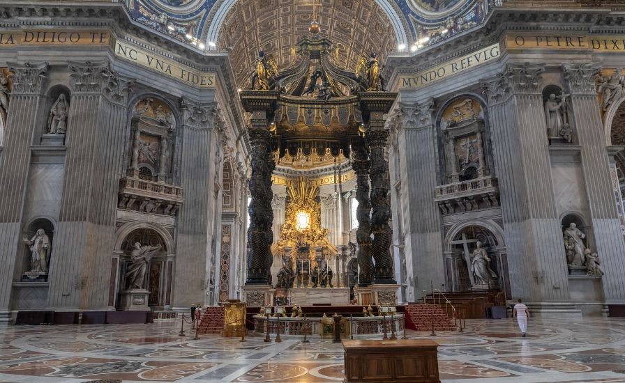 Interior of a cathedral with statues and a large altar, featuring The Papal Tombs.